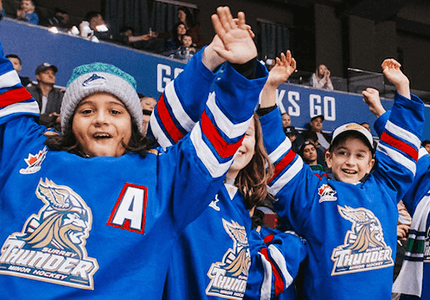 Excited minor hockey group members watch the Vancouver Canucks from the stands.